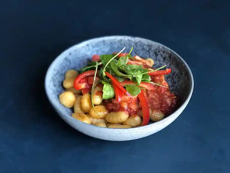 Stegt gnochetti med svinekød i tomatsauce, grønt og rucola
